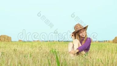 可爱的女孩戴着牛仔帽，在乡村田野上与干草堆合影。 穿牛仔服的少女装扮
